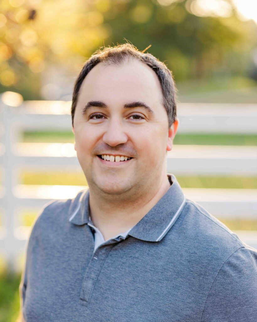 Jeff. wearing gray polo shirt with a white picket fence behind him